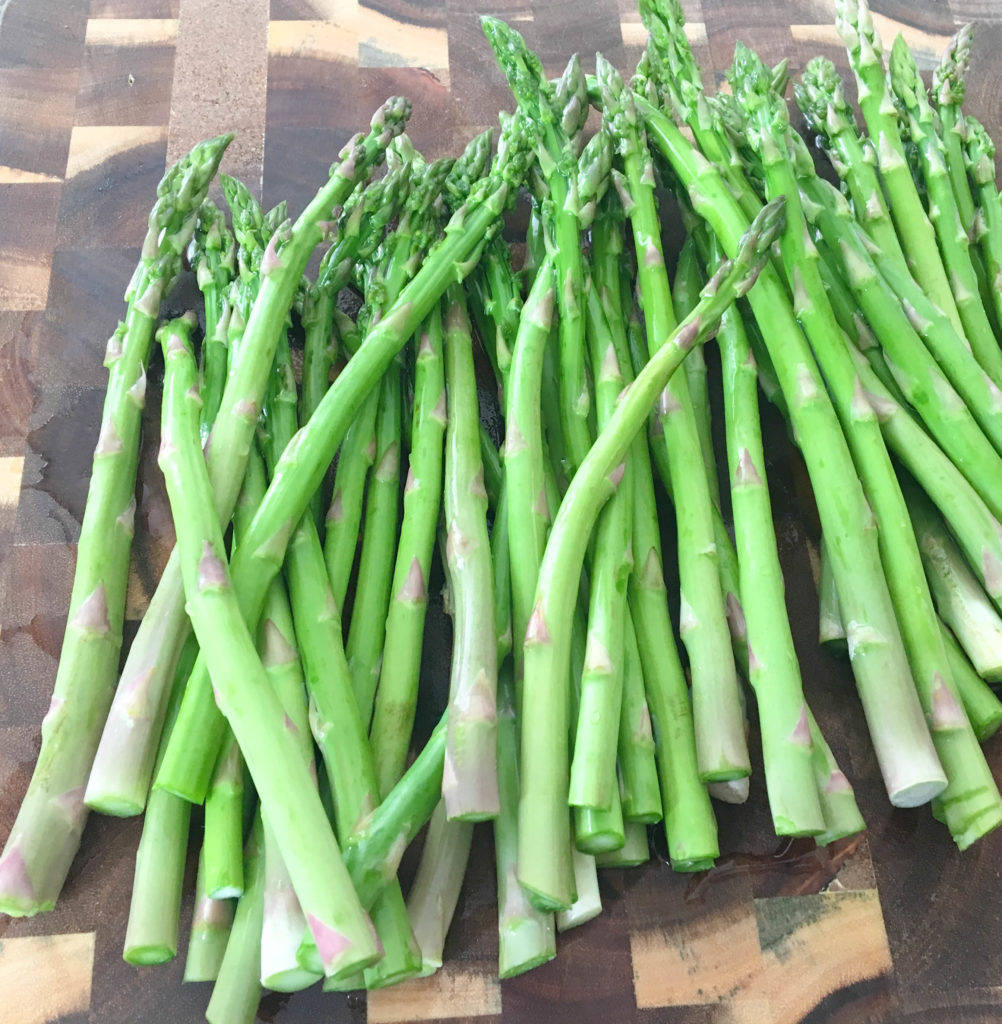 bunch of asparagus on a cutting board.